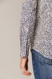 Close-up mouw van een man met blauw-wit met bruine print overhemd.