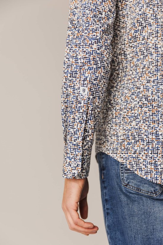 Close-up mouw van een man met blauw-wit met bruine print overhemd.