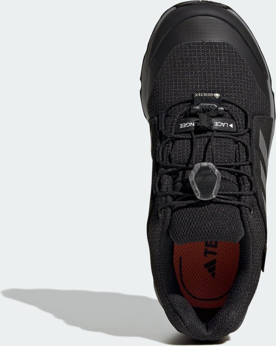 Bovenkant van zwarte kinderschoen met veters, GORE-TEX-logo en Adidas-strepen.