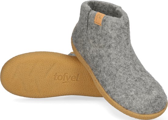 Grijze wollen pantoffel met leren label, bruine zool zichtbaar, van schuin van voren gezien.