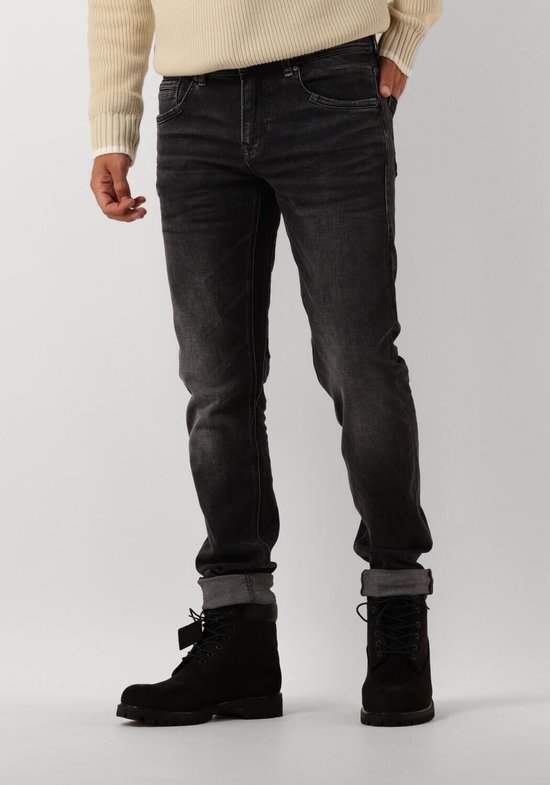 Voorkant man in grijze jeans met opgerolde broekspijpen en zwarte laarzen