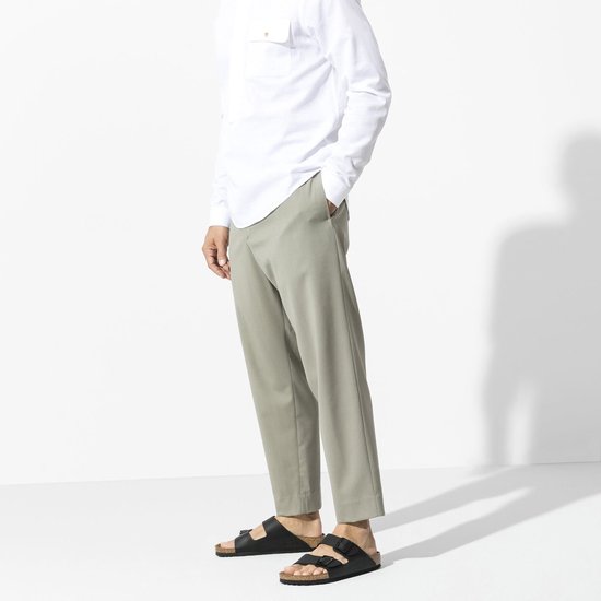 Man draagt zwarte Birkenstock Arizona slippers met chino broek.