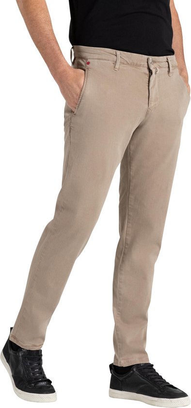 Mannelijke model in een beige chino broek met zwarte sneakers.