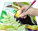 Hand kleurt een tekening van een toekan met een roze pigment brush pen.