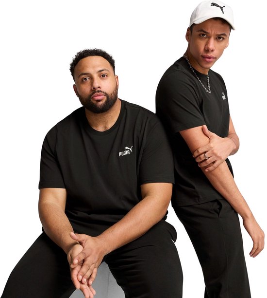 Twee mannen in zwarte Puma T-shirts en broeken. Eén man zit, de ander staat achter hem. Een draagt een witte pet.