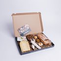 Gouden kaas, worstjes, pretzels, koekjes en een kaart in een doos.