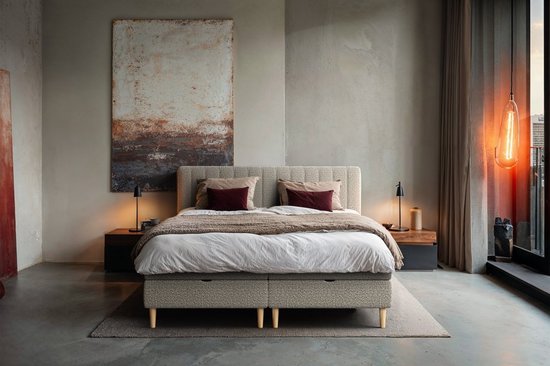 Beige boxspring EDEN met opbergruimte, twee kussens en een deken in een slaapkamer.