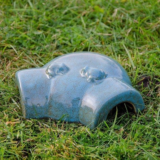 Maisonnette pour grenouilles en céramique bleu-vert avec deux petites figurines de grenouilles, posée dans l'herbe. Finition émaillée craquelée.