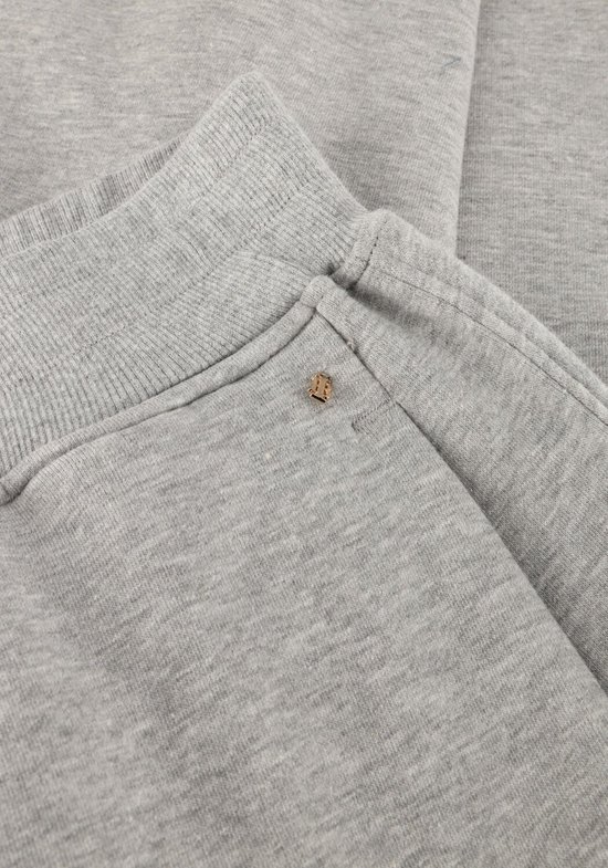 Detailopname van de tailleband van een grijze joggingbroek met gouden logoknoop.
