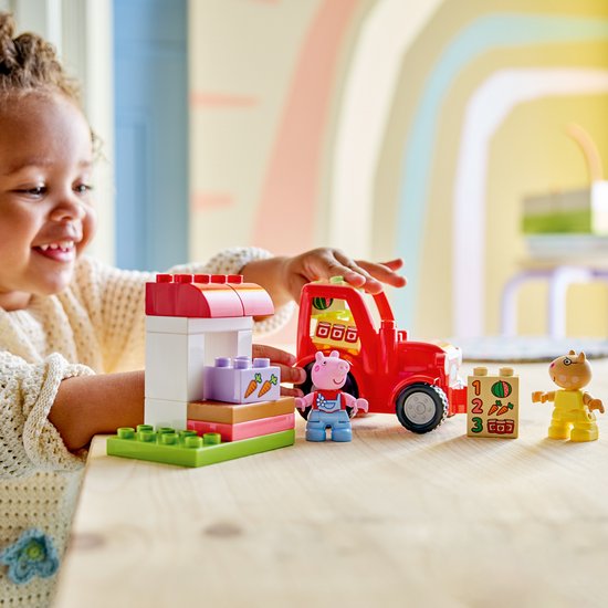 Kind speelt met LEGO Duplo Peppa Pig tractor, marktkraam, Peppa en George.