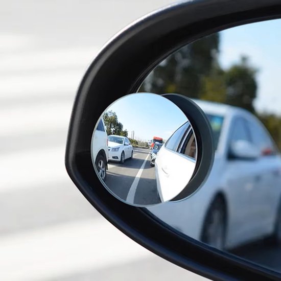Ronde dodehoekspiegel op zwarte autospiegel met reflectie van witte auto's op de weg.