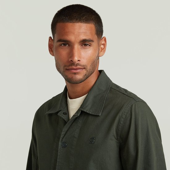 Close-up van man in donkergroen G-Star jack met beige T-shirt.