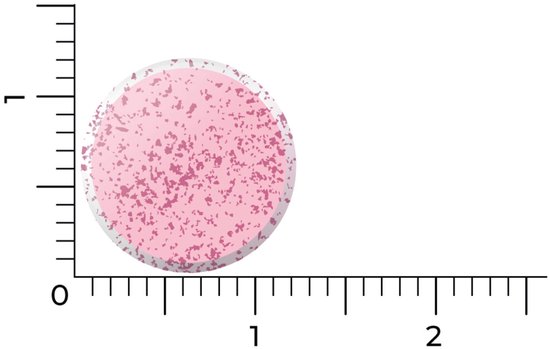 Een enkele roze smelttablet met kleine rode spikkels, afgebeeld naast een liniaal.