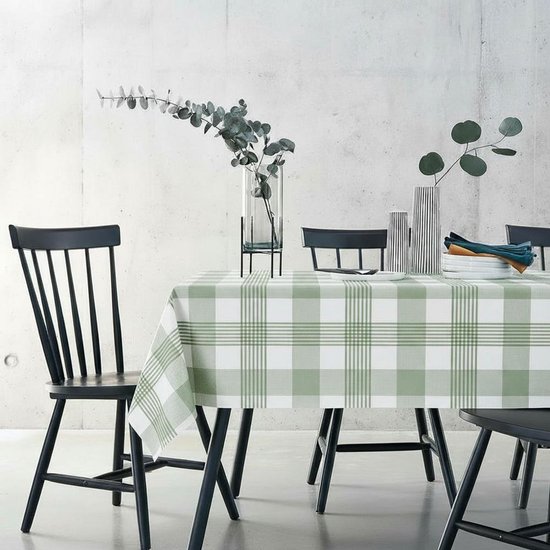 Tafel gedekt met een groen en wit geruit tafelzeil, in een moderne eetkamer met betonnen muur.