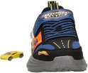 Achterkant van een zwarte sneaker met blauwe en oranje accenten en een kleine gele speelgoedauto.