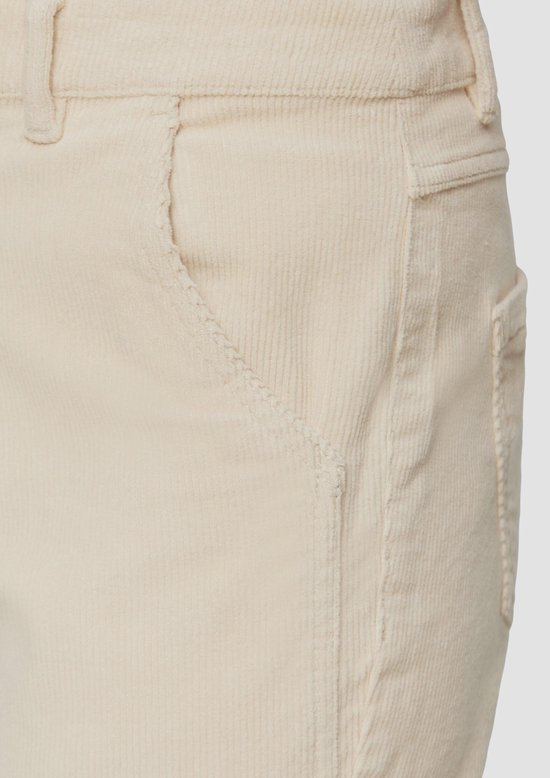 Detailopname van de crème kleurige corduroy broek, met zichtbare naden en zakken.