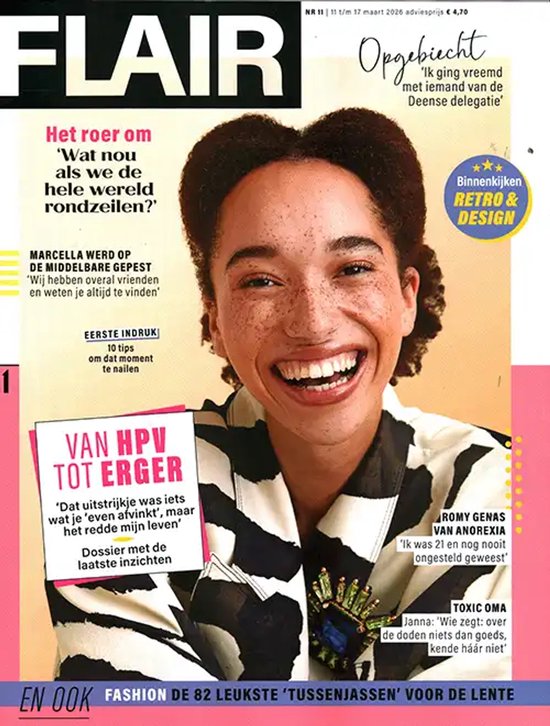 Vrolijk lachende vrouw met sproeten, draagt een zwart-wit gestreept shirt met een groene broche.