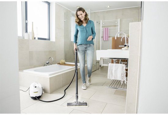 Femme utilisant un nettoyeur vapeur dans une salle de bain carrelée de blanc.