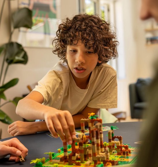 Een jongen speelt LEGO Monkey Palace met een bruine, oranje en beige toren.
