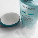 Bouteille de shampoo Kérastase Résistance Bain Force Architecte à côté d'un bouchon turquoise et argenté.