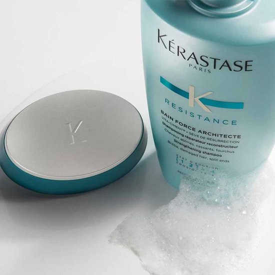 Bouteille de shampoo Kérastase Résistance Bain Force Architecte à côté d'un bouchon turquoise et argenté.