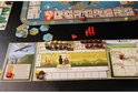 Bordspel met speelkaarten, miniatuurfiguren, tegels en een spelbord met een kaart van grasland.