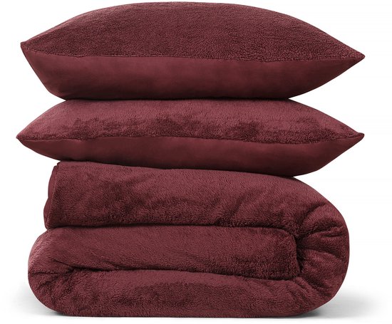 Taies d'oreiller empilées en peluche teddy bordeaux et une housse de couette pliée sur fond blanc.