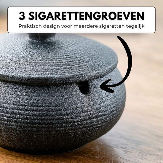 Zwarte keramische asbak met deksel, met pijl die naar 3 sigarettensleuven wijst.