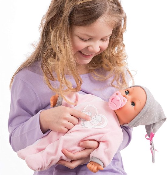Meisje houdt een babypop vast die een roze slaappakje en grijze stippenmuts draagt.