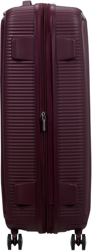Burgondische koffer met ritssluiting, handvat en vier wielen. Gekarteld design met 'American Tourister' tekst.