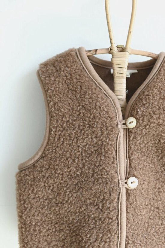 Detail van bruin wollen kinder vest met bruine biezen en twee knopen.