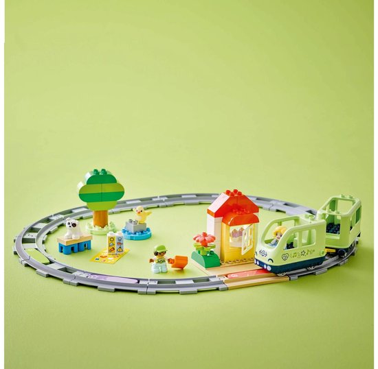 Train LEGO Duplo vert clair sur rails, avec maisonnette, arbre, figurines et chien.