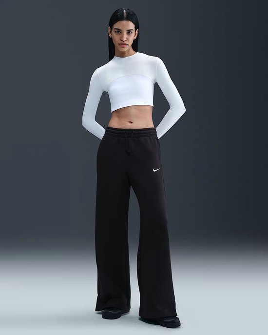 Model in een zwarte Nike sportbroek met wit logo, gecombineerd met witte top.
