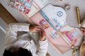 Meisje plakt stickers in een kartonnen poppenhuis speelset met kamers en meubels.