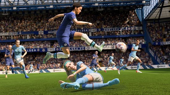 Een Chelsea-speler in blauw shirt springt om de bal te koppen, een Manchester City-speler in lichtblauw valt op het veld.