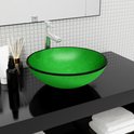 Lavabo rond vert en verre avec un bord noir sur un plan de travail noir.