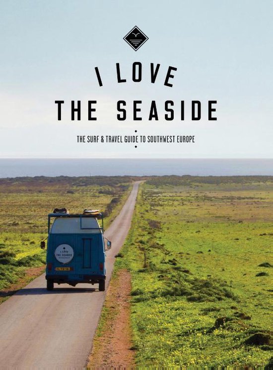 Blauwe camperbus rijdt op een weg in een landschap met uitzicht op de oceaan. Boven de tekst 'I Love The Seaside'.