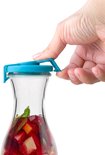 Hand sluit de turquoise deksel op een glazen karaf met fruit.
