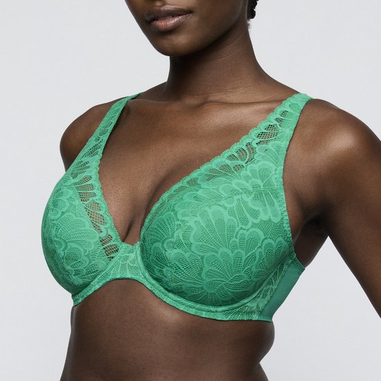Model draagt een groene kanten bh met bloemenpatroon en diep decolleté.