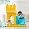 Château jaune avec arche, une glissière bleue et un petit garçon, avec un chien blanc au sol.