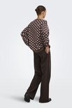Model van achteren gezien in een bruine sweater met witte polkadots en een wijde bruine broek.