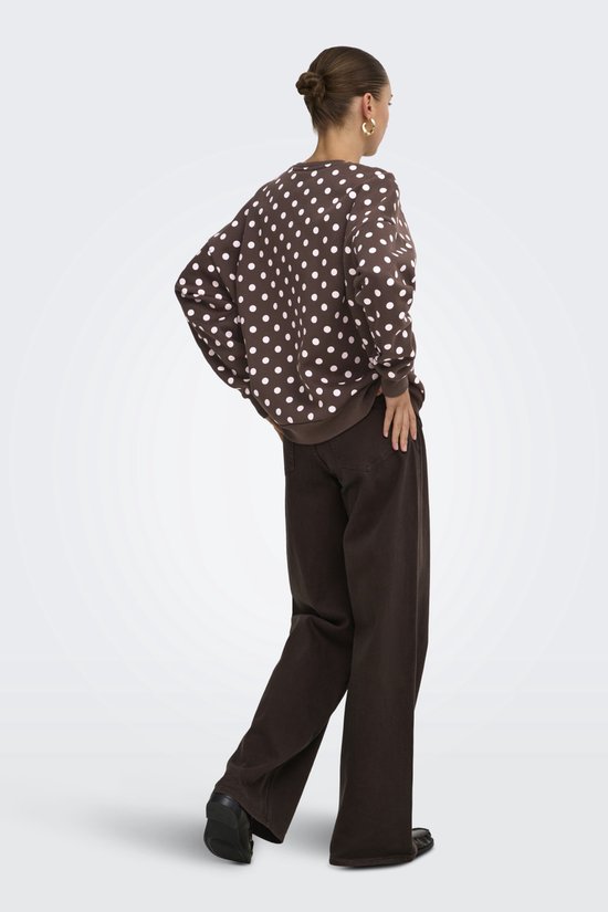Model van achteren gezien in een bruine sweater met witte polkadots en een wijde bruine broek.