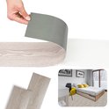 Zelfklevende pvc-plank in eikenlook wordt losgetrokken, naast een slaapkamerinterieur als voorbeeld.