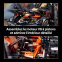 Close-up van de motor van de LEGO-auto en een hand die de oranje cockpit aanpast. "Assembleer de V8-zuigermotor en bewonder het gedetailleerde interieur".