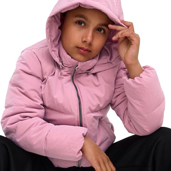 Meisje in roze pufferjack met capuchon, zittend met hand op voorhoofd.