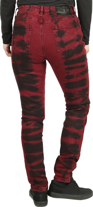Rode skinny jeans met zwarte batikprint, gedragen door een vrouw.