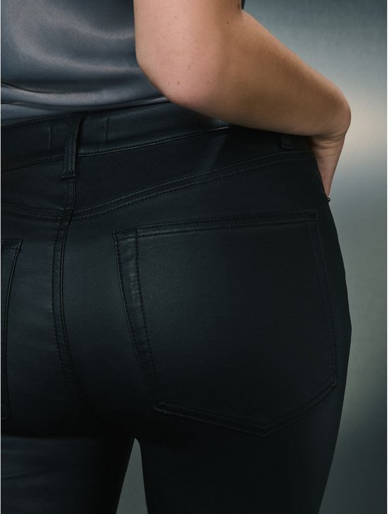 Close-up van de achterkant van een model in zwarte skinny jeans met coating.