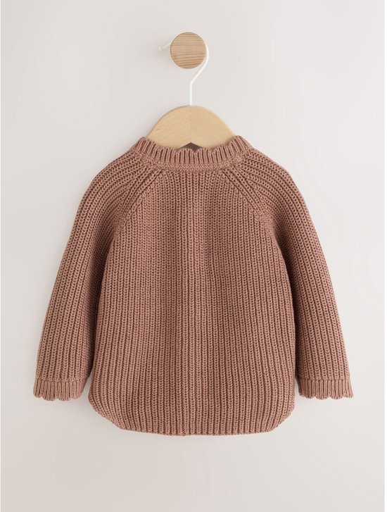 Een bruin gebreid babyvestje hangt aan een houten hanger.