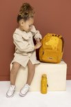 Meisje met een beige jurk zittend naast een gele 'Mr. Giraffe' rugzak met een waterfles.