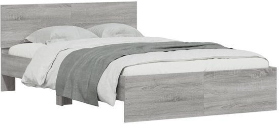 Grijs eiken houten bedframe met witte lakens en grijze deken, gezien vanaf de zijkant.